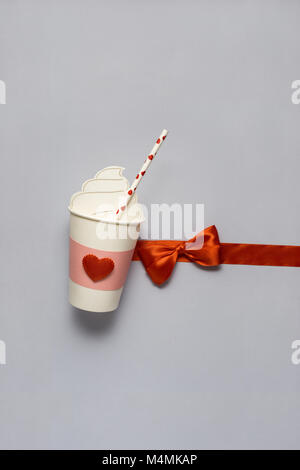Concetto creativo foto di take away tazza da caffè con cuori su sfondo grigio. Foto Stock