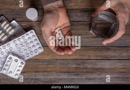 L'uomo è di andare a prendere la medicina pillole e capsule e bere acqua Foto Stock