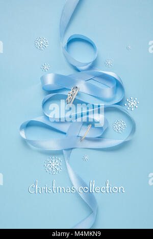 Concetto creativo foto di albero di Natale fatto di nastro e gioielli su sfondo blu. Foto Stock