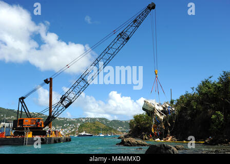 Coast Guard i membri di sorvegliare le operazioni di risolvere Marine Group, una risposta contratta company, come essi sollevare una nave spostato dai recenti uragani dal litorale di acqua Island, St. Thomas USVI, Feb 10, 2018. La costa di protezione viene qui, a sostegno degli Stati Uniti Isole Vergini dipartimento di pianificazione e delle risorse naturali, per ridurre l'inquinamento e rimuovere le navi spostato dagli uragani di Irma e Maria come parte del supporto di emergenza funzione 10 operazioni. Foto Stock