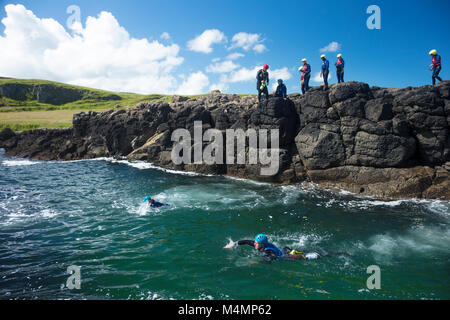 Gruppo Coasteering al Sloc, Dunseverick, Causeway Coast, paese di Antrim, Irlanda del Nord. Foto Stock