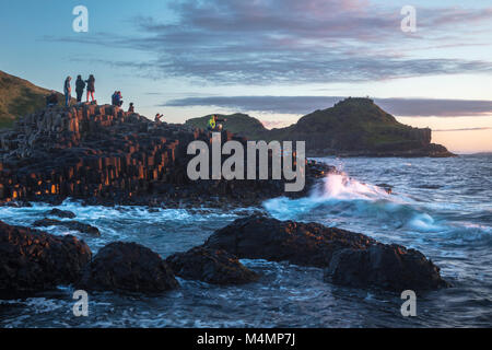 Sera visitatori presso il Selciato del gigante, paese di Antrim, Irlanda del Nord. Foto Stock