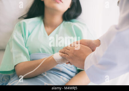 Gentile uomo medico mani tenendo la mano del paziente seduto alla scrivania di incoraggiamento, empatia, tifo e supporto durante la visita medica. Bad nuovo Foto Stock