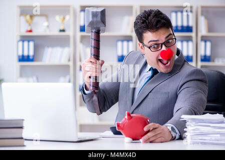 Clown imprenditore con un salvadanaio e un martello Foto Stock