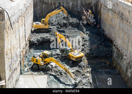 Scavatrici scavare in corrispondenza di un sito di costruzione di una strada e di una fermata della metropolitana. Trasporto Baggers sporco a un livello superiore per fare spazio per la metropolitana di macchina di scavo. Foto Stock