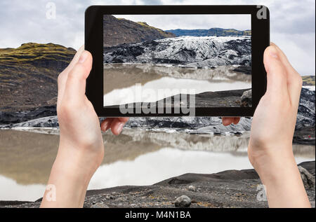 Concetto di viaggio - fotografie turistiche acqua di fusione e il ghiacciaio Solheimajokull (Sud lingua glaciale di Myrdalsjokull tappo di ghiaccio) in Katla geoparco in Icel Foto Stock