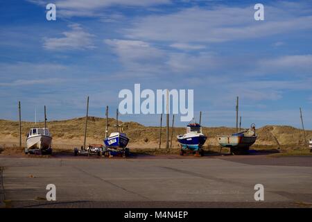 Quattro piccole imbarcazioni parcheggiato a Port Erroll, con la Sanddunes di Cruden Bay in background. Aberdeenshire, Scotland, Regno Unito. Foto Stock
