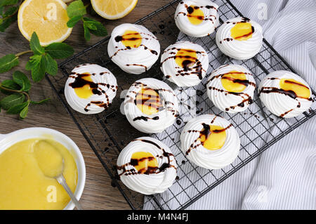 Delicato, croccante mini dessert " Pavlova' riempita con curda di limone e cioccolato topping sul rack Foto Stock