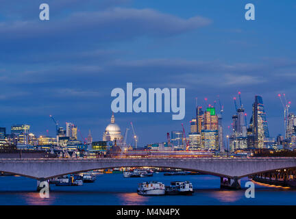 La città di Londra e la Cattedrale di St Paul dal Giubileo Bridge come i palazzi si illumina al tramonto. Foto Stock