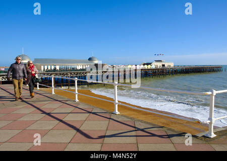 Hastings, East Sussex Regno Unito. Un paio di passeggiare lungo la passeggiata sotto un cielo blu senza nuvole su una mite giornata di sole in inverno. Foto Stock