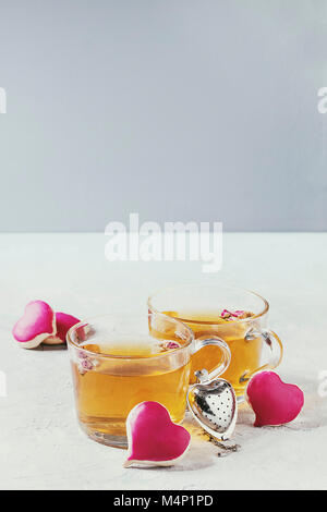 L'amore il giorno di San Valentino biglietto di auguri con due bicchieri di tè caldo e forma di cuore biscotti con glassa rosa e filtro di tè bianco sopra la tabella. Copia Foto Stock