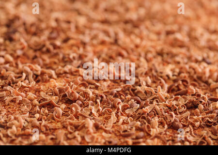 Scaglie di cioccolato, extreme macro. Close up di sottili scaglie di cioccolato e riccioli tritato manualmente sulla torta texture. Migliore immagine di gustoso riccioli di cioccolato Foto Stock