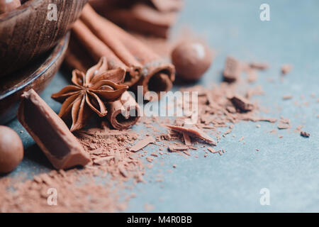 Testata con pezzetti di cioccolato e di spezie, stelle di anice e cannella e cacao su un sfondo di pietra. La cottura di dolci e home concetto. Foto Stock