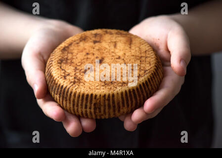 Rustico formaggio gourmet nelle mani del casaro, vicino. Condimento piccante fatto a mano il formaggio. Foto Stock