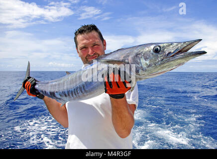 La pesca in mare profondo, Big game pesca. cattura del pesce. Lucky fisherman tenendo una massiccia wahoo pesce Foto Stock