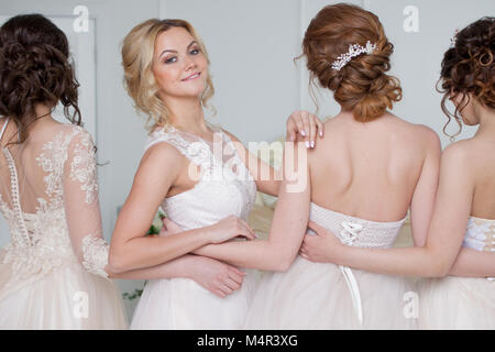 Sposa nel salone per matrimoni. Quattro bellissima ragazza sono in ogni altra delle armi. Close-up gonne di pizzo Foto Stock