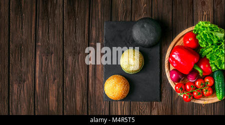 Da sopra vista di tre diversi panini hamburger e verdure fresche a bordo. Foto Stock