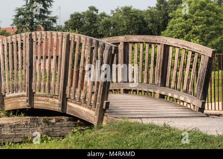 Poco curvo pedonale di ponte di legno in un parco Foto Stock