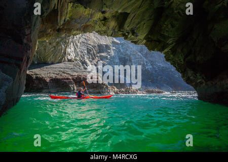 Sea kayaker di esplorare una grotta nei pressi di Glencolmcille, County Donegal, Irlanda. Foto Stock