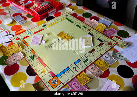 Scheda di monopolio gioco che viene giocato da bambini all'interno di una casa su un tavolo con la tovaglia colorato a metà termine in Carmarthenshire Wales UK Foto Stock