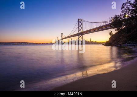 Classic vista panoramica dello skyline di San Francisco con il famoso Oakland Bay Bridge illuminato nel bellissimo golden luce della sera al tramonto in estate, San Foto Stock