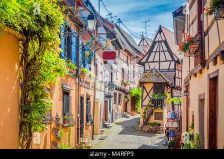 Suggestiva scena di strada con case colorate nella storica città di Eguisheim su una bella giornata di sole con cielo blu in estate, Alsazia, Francia Foto Stock