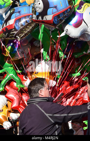 Un uomo vendita di palloncini o un palloncino venditore in un centro della città con un grande numero di palloncini colorati marea insieme con una corda e riempito di elio. Foto Stock
