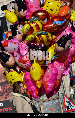Una signora o donna vendita femail riempito di elio giocattoli per bambini palloncini in un centro commerciale sono di una città. palloncini colorati in vendita dal venditore. Foto Stock