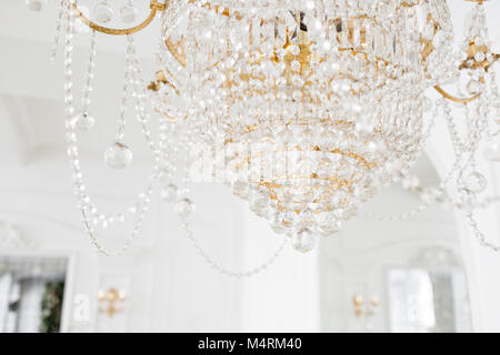 Costoso interni. Grande Lampadario elettrica fatta di perline di vetro trasparenti. Soffitto bianco decorato con stucchi. White modellata. Modanature elemento dal gesso. Foto Stock