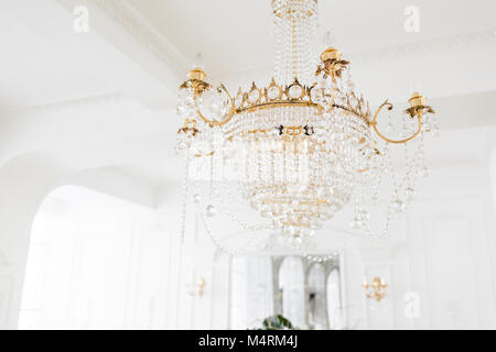 Costoso interni. Grande Lampadario elettrica fatta di perline di vetro trasparenti. Soffitto bianco decorato con stucchi. White modellata. Modanature elemento dal gesso. Foto Stock