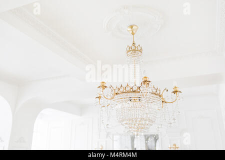 Costoso interni. Grande Lampadario elettrica fatta di perline di vetro trasparenti. Soffitto bianco decorato con stucchi. White modellata. Modanature elemento dal gesso. Foto Stock