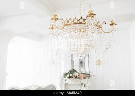 Costoso interni. Grande Lampadario elettrica fatta di perline di vetro trasparenti. Soffitto bianco decorato con stucchi. White modellata. Modanature elemento dal gesso. Foto Stock