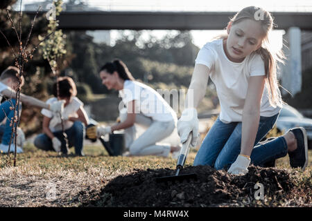 Bella ragazza bionda lavora con un rastrello Foto Stock