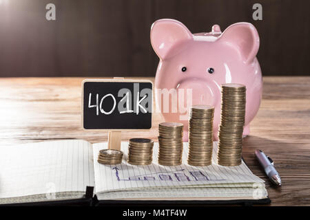 Aumentando il concetto di profitto con Piggybank, Coin impilati, e il grafico su notebook sopra il tavolo in legno Foto Stock