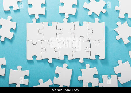 Vista in elevazione del White Jigsaw Puzzle su sfondo blu Foto Stock