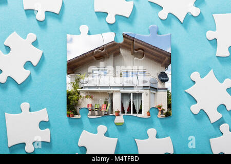 Close-up di casa incompleta Puzzle su sfondo blu Foto Stock