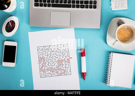 Vista in elevazione di un labirinto sulla carta con forniture di ufficio sopra la scrivania in ufficio Foto Stock