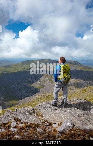Escursionista guardando oltre la penisola di Beara dalla cima della collina di affamati, County Cork, Irlanda. Foto Stock