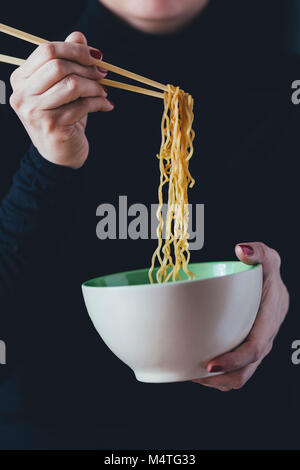 Donna detiene una ciotola di tagliolini con bacchette Foto Stock