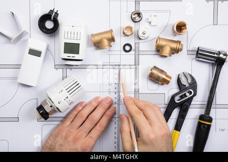 Vista in elevazione di un architetto del piano di disegno con termostato e strumenti di lavoro su Blueprints Foto Stock