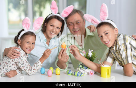 La famiglia felice di quattro indossando orecchie di coniglietto e pittura delle uova di Pasqua Foto Stock