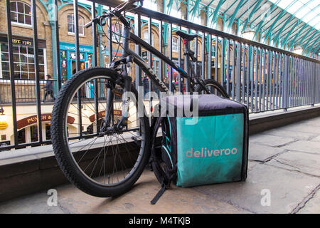 Un parcheggiato Deliveroo pilota della moto e Deliveroo bag in Covent Garden, Londra Foto Stock