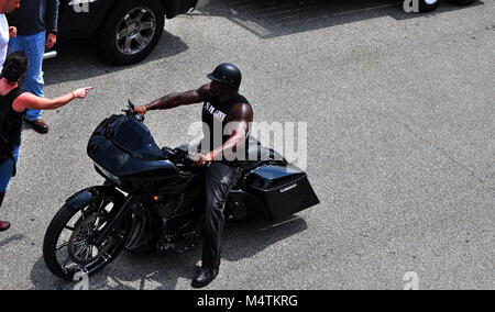 Uomo seduto fermo sulla sua motocicletta personalizzata con bisacce Foto Stock