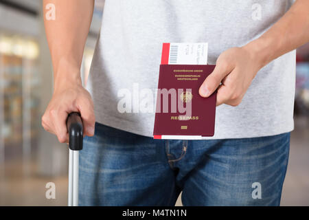 Persona della mano con ritenuta bagagli Passaporto e carta di imbarco biglietti all'aeroporto Foto Stock