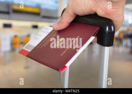 Persona della mano con ritenuta bagagli Passaporto e carta di imbarco biglietti all'aeroporto Foto Stock