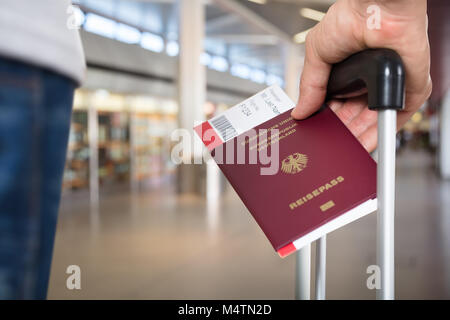 Persona della mano con ritenuta bagagli Passaporto e carta di imbarco biglietti all'aeroporto Foto Stock