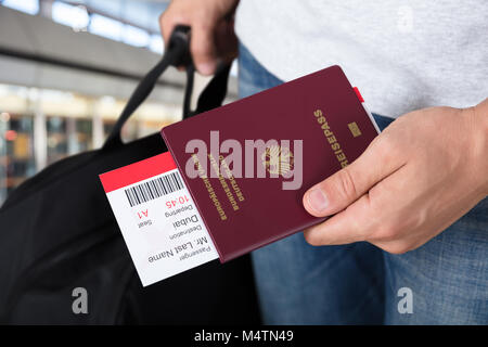 Persona della mano con ritenuta bagagli Passaporto e carta di imbarco biglietti all'aeroporto Foto Stock