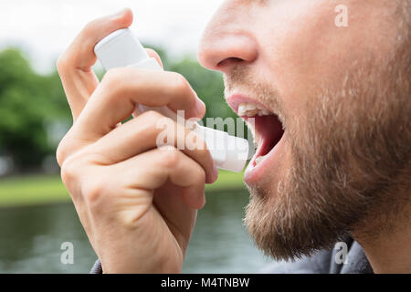 Close-up di barba uomo con asma Inalatore per essere sano Foto Stock