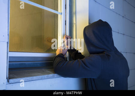 Close-up di rapinatore nel cofano usando il piede di porco Rosso Per aprire la finestra in vetro Foto Stock