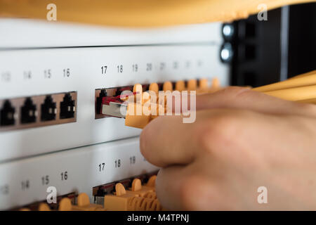 Close-up di ingegnere collegando i cavi nel Server nel centro dati Foto Stock